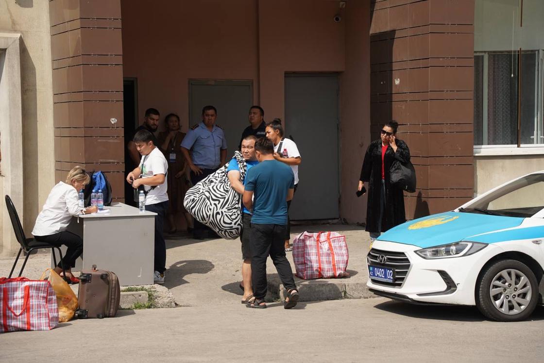 Жители многоэтажки выходят с пакетами и чемоданами