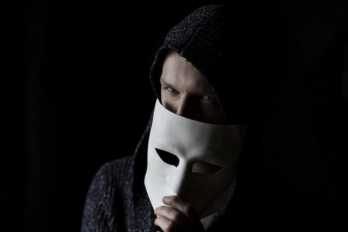 Злой мужчина прячет лицо за маской