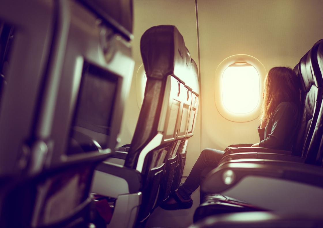Девушка сидит в самолете на месте у окна