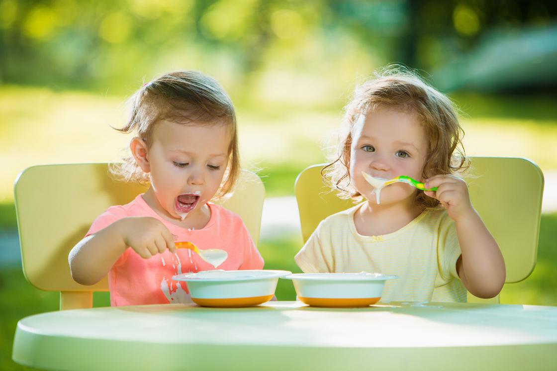 Две маленькие девочки едят кашу