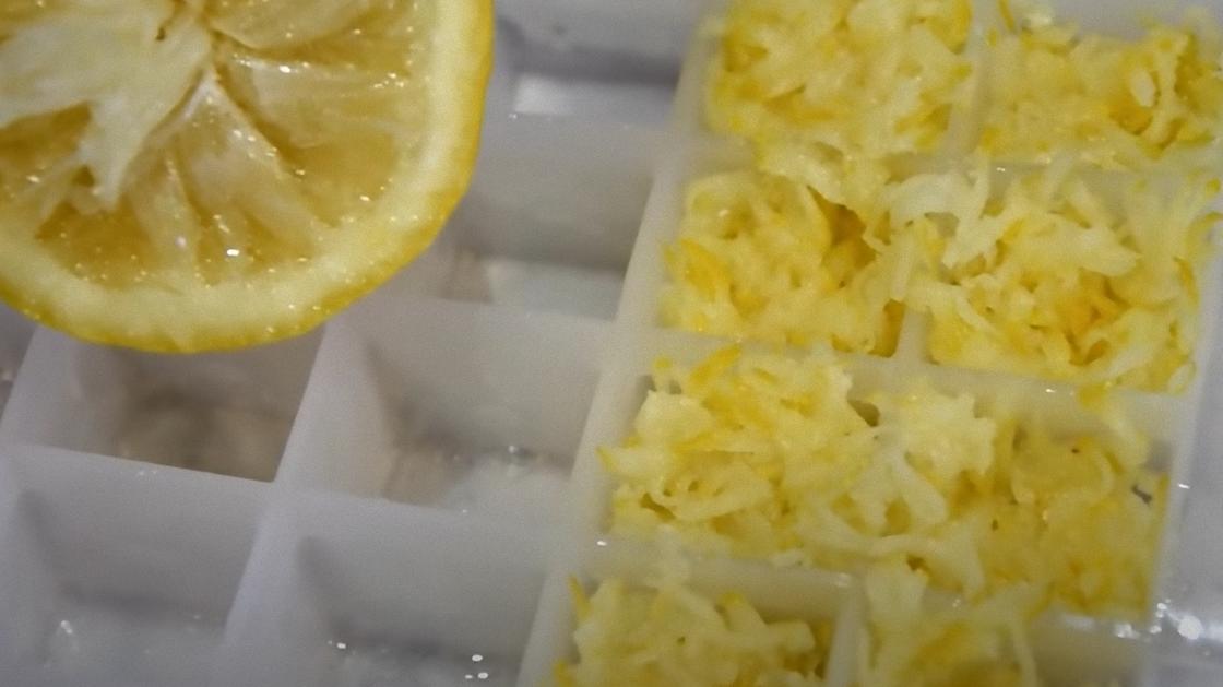 Кусок лимона и тертая цедра в контейнере для льда