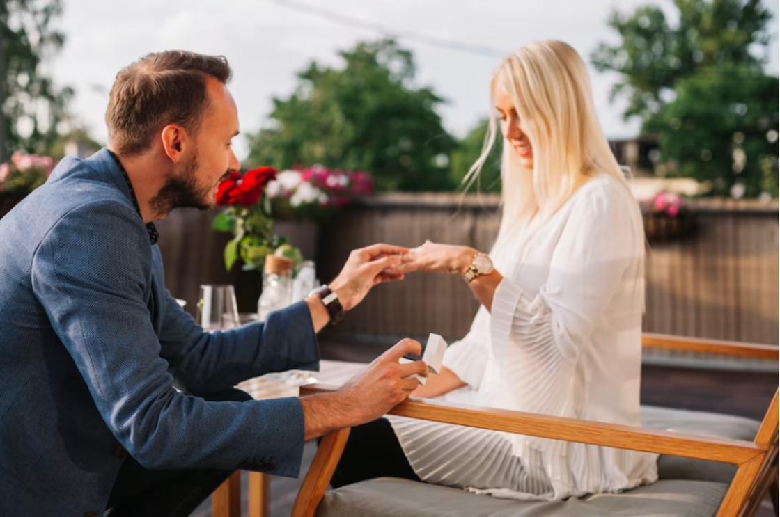 Мужчина надевает помолвочное кольцо на руку женщины