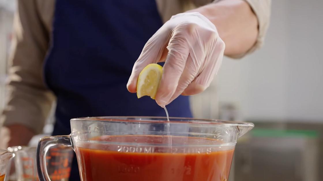 Мужчина выдавливает сок лимона в томатный соус