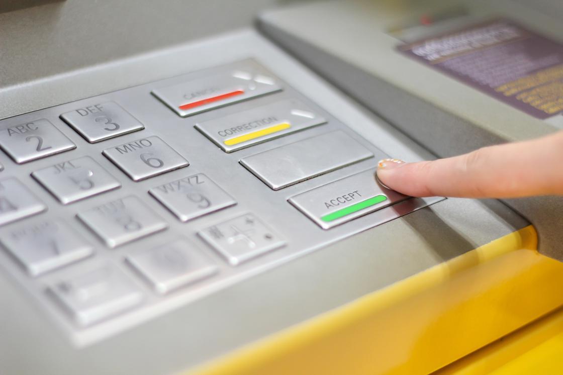 Палец нажимает на клавиатуре банкомата кнопку ACCEPT
