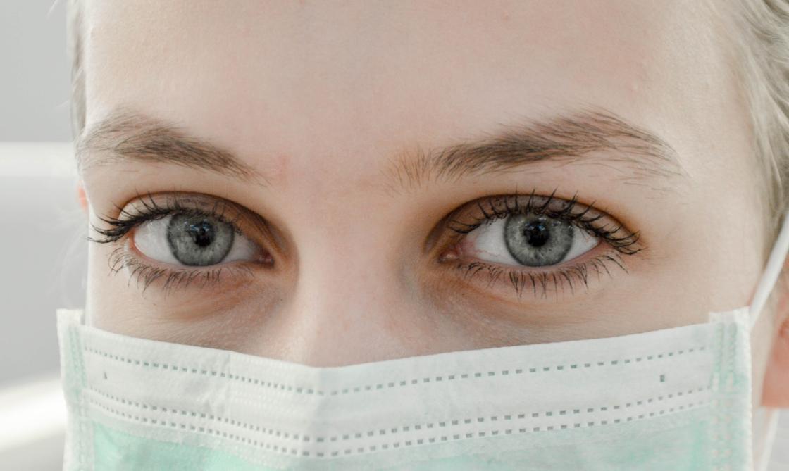 Женские глаза над медицинской маской, которой прикрыто лицо