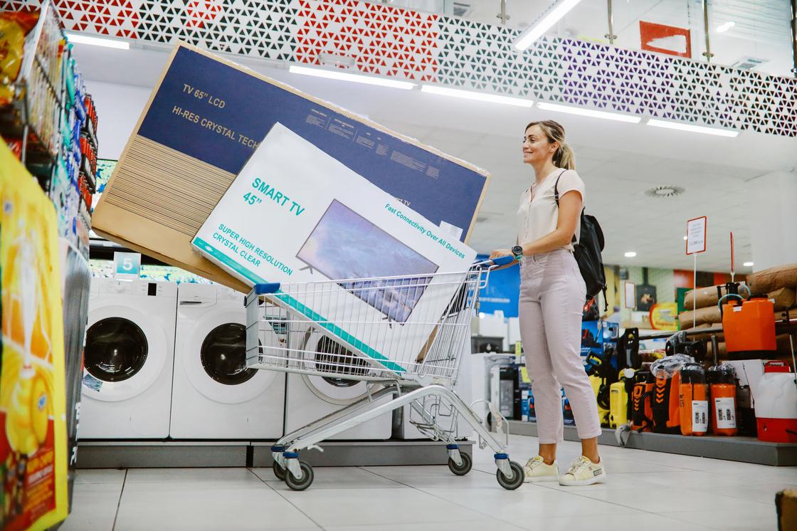 Женщина покупает телевизоры в магазине электроники