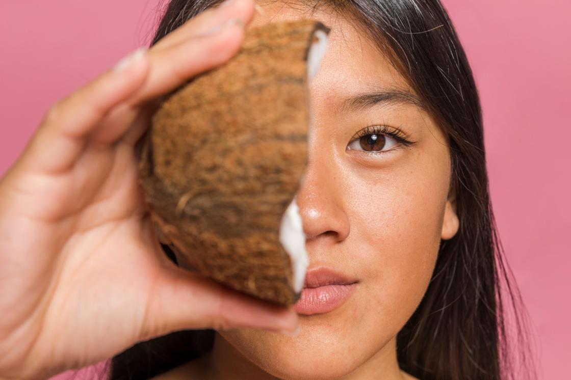 Девушка держит в руке половину кокосового ореха