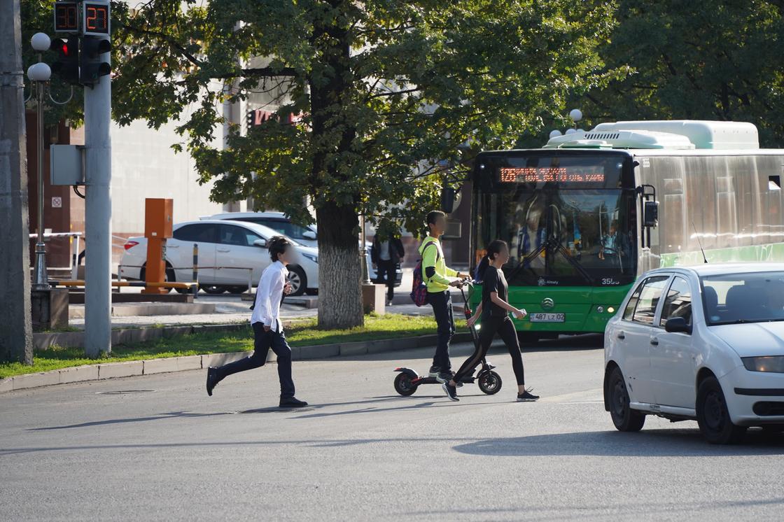 Люди, машины и автобус на дороге в Алматы