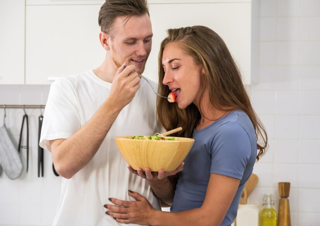 Мужчина кормит девушку салатом