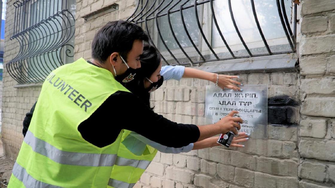 Волонтеры используют трафарет для надписей