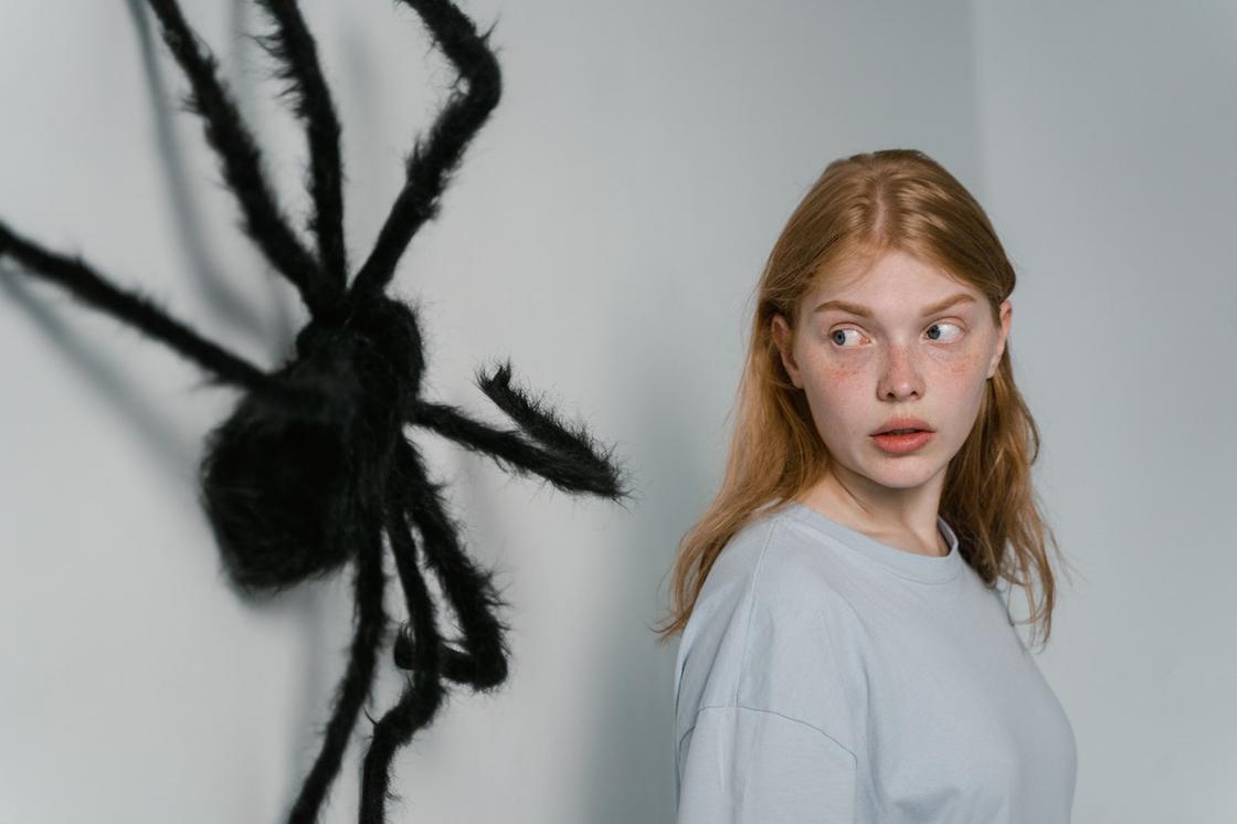 Девушка испуганно смотрит на большого паука