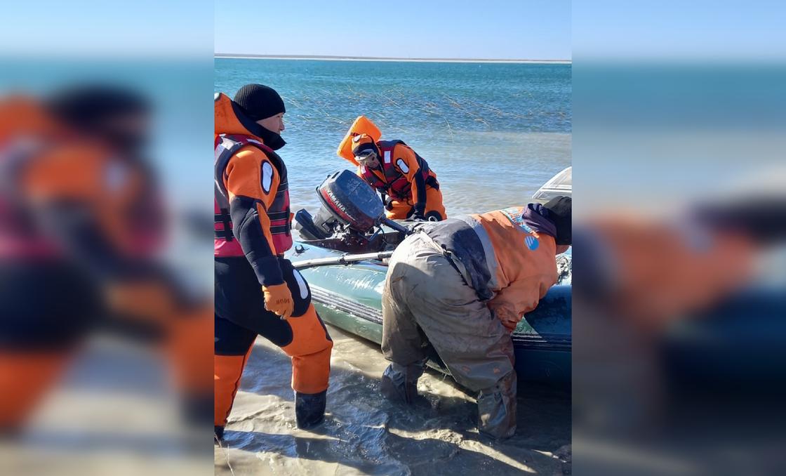 Спасатели вытаскивают на берег лодку