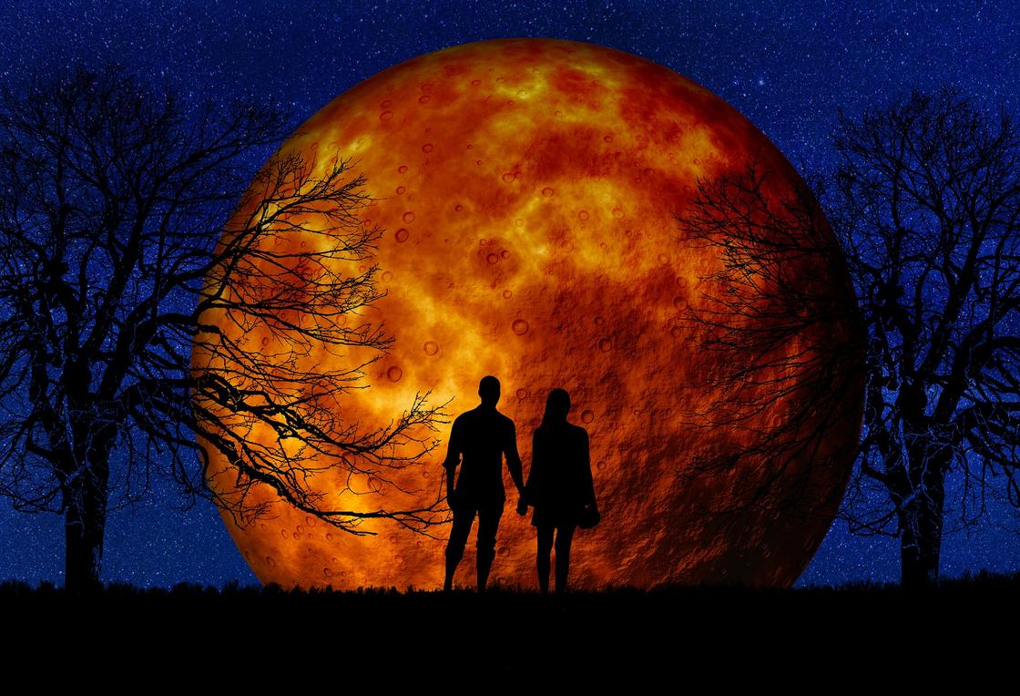 Пара держится за руки на фоне полной Луны