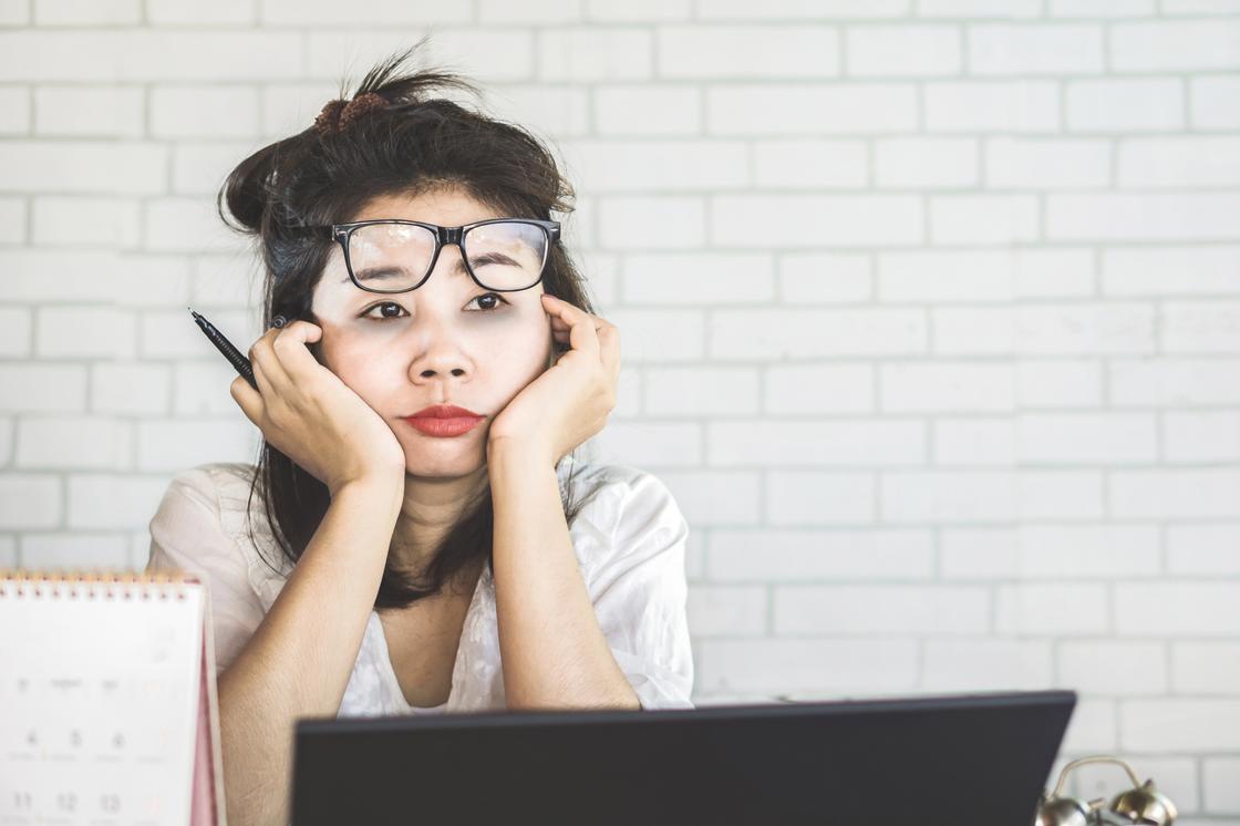 Уставшая женщина в очках сидит за компьютером