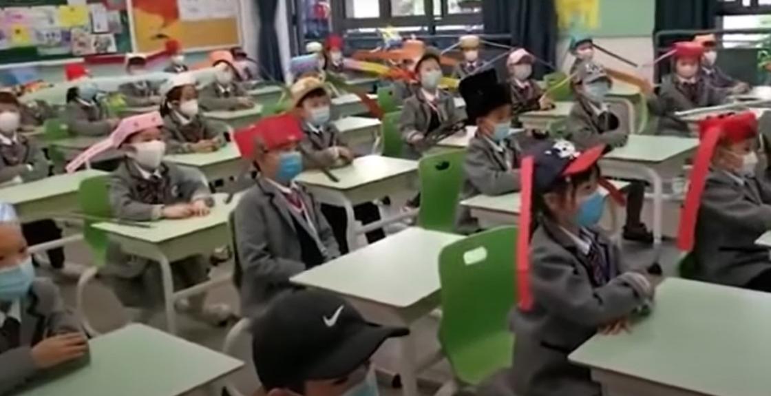 Школьники носят "безопасные" шляпы против коронавируса в Китае (видео)