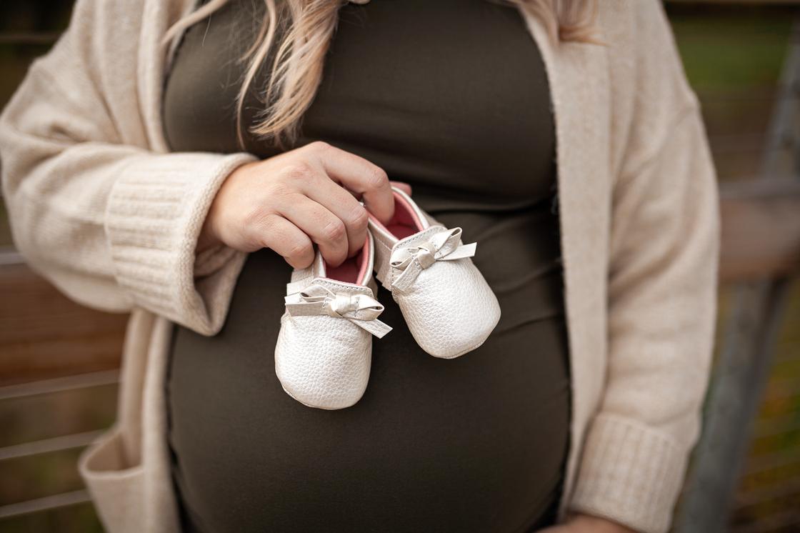 Беременная женщина держит детскую обувь