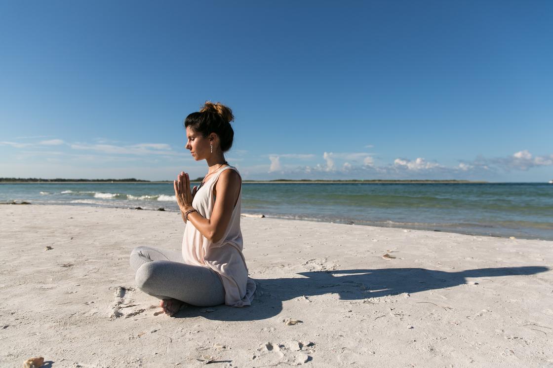 Беременная женщина сидит на берегу моря