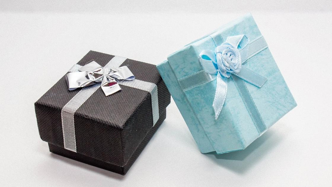 Квадратные коробки со съемными крышками серого и голубого цвета перевязаны лентами. Одна коробка украшена бантом, а другая розой из ленты