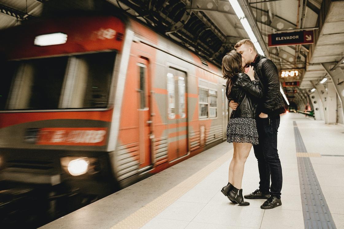 Влюбленные целуются рядом с проезжающим мимо поездом метро