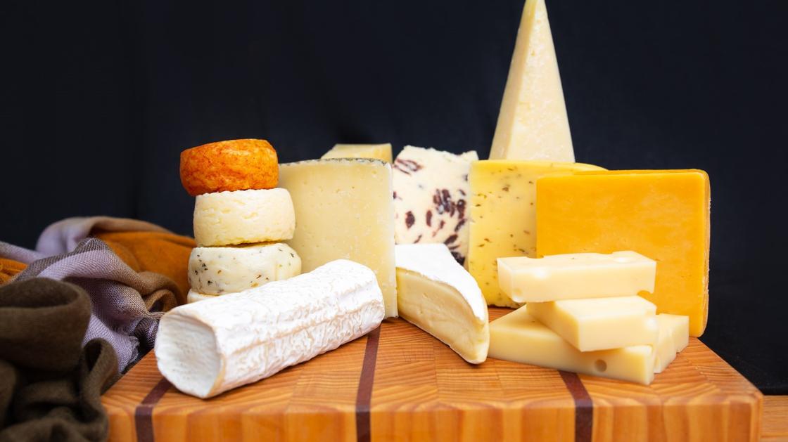 На столе выложены куски разных сортов сыра