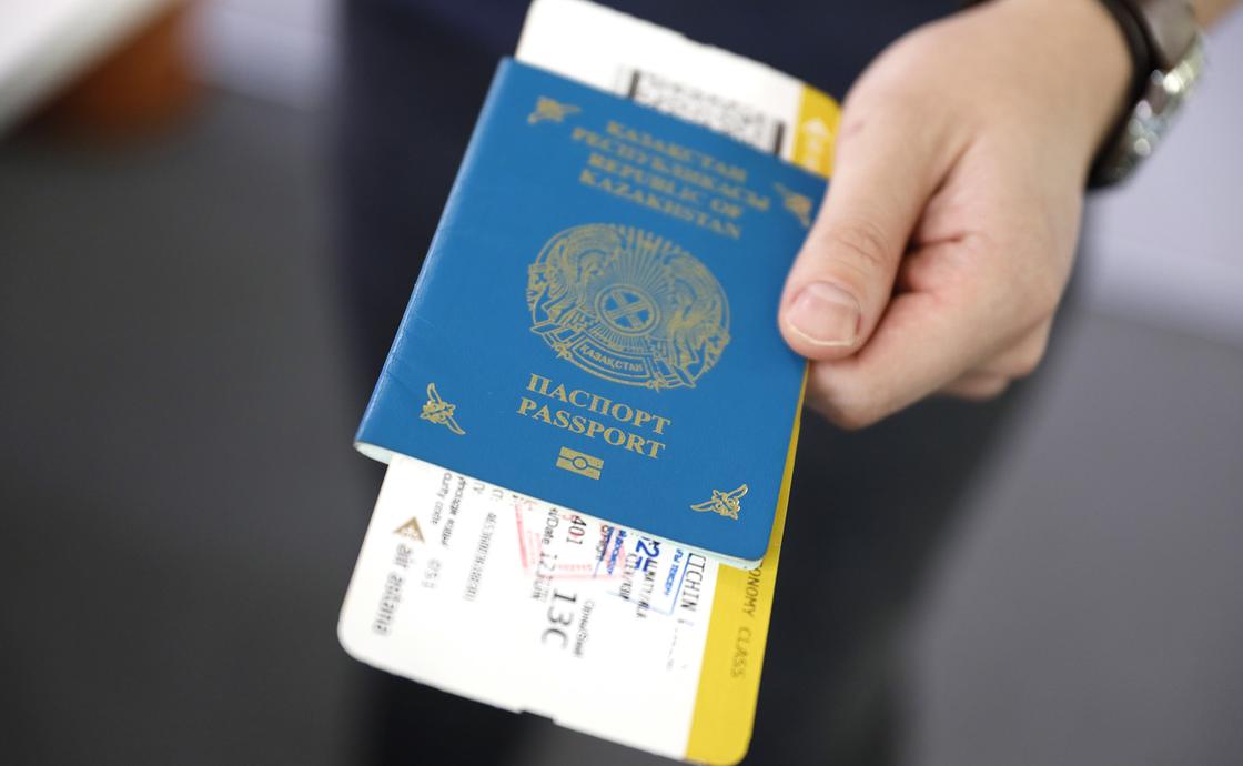 Мужчина держит паспорт с билетами на самолет