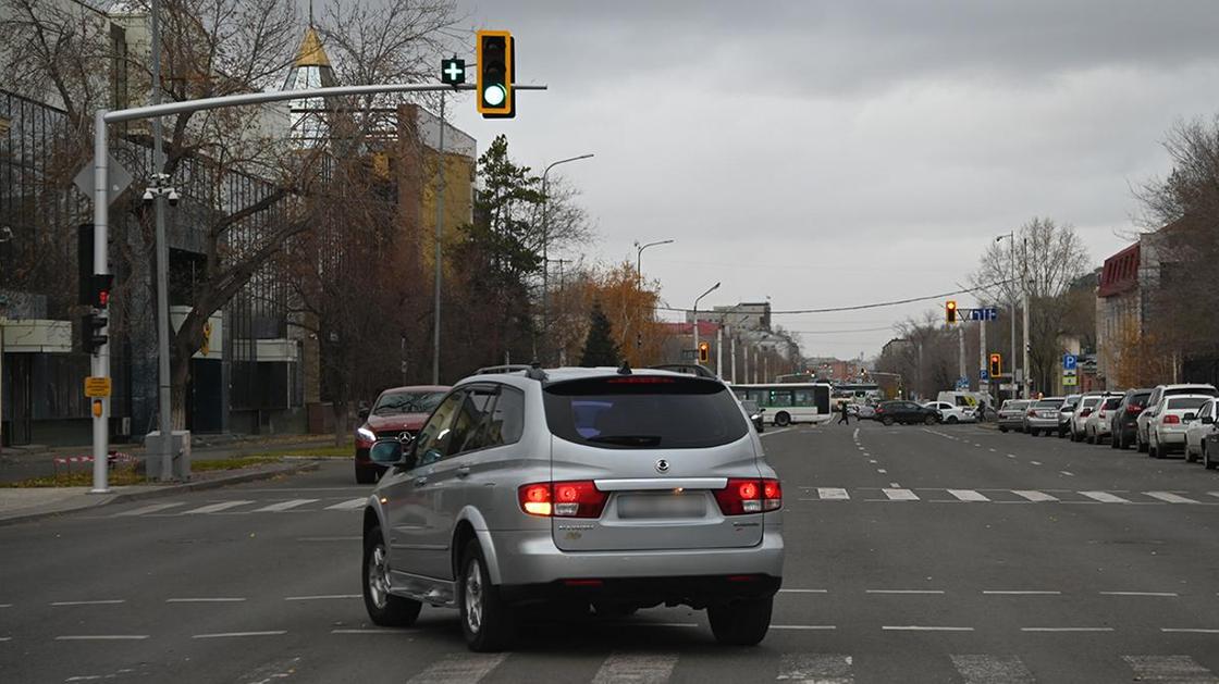 Автомобиль проезжает перекресток с зеленым "плюсом" возле светофора
