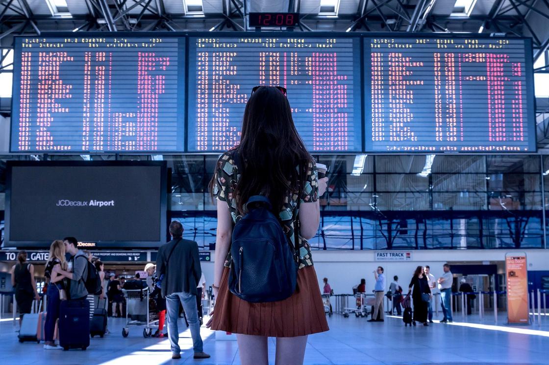 Девушка стоит перед электронным табло в аэропорту