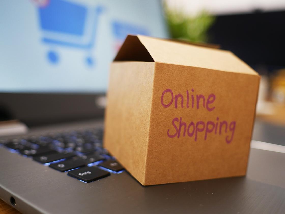 Картонная коробка с надписью онлайн-шоппинг на ноутбуке