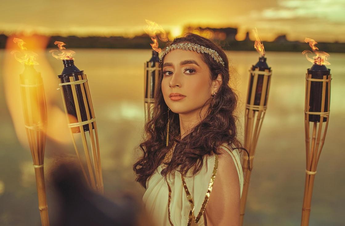 Девушка в образе царицы Египта Клеопатры стоит в окружении факелов