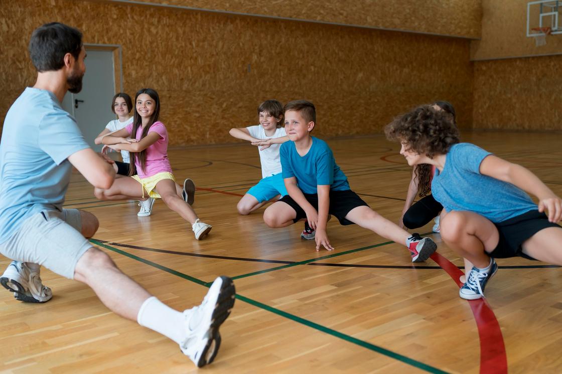 Мужчина и дети занимаются спортом в спортзале