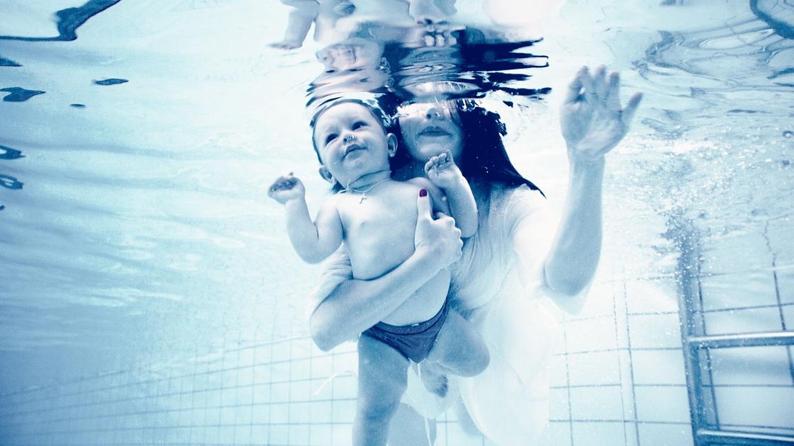 Мама с малышом купаются в бассейне
