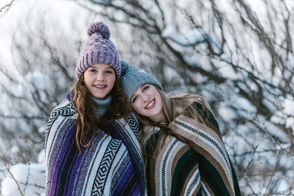 Две девушки в пледах на фоне зимнего пейзажа