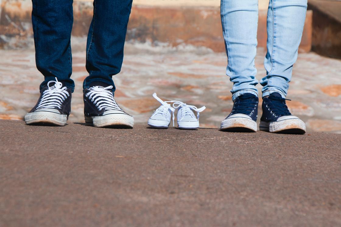 Мужчина и женщина стоят рядом с детской обувью