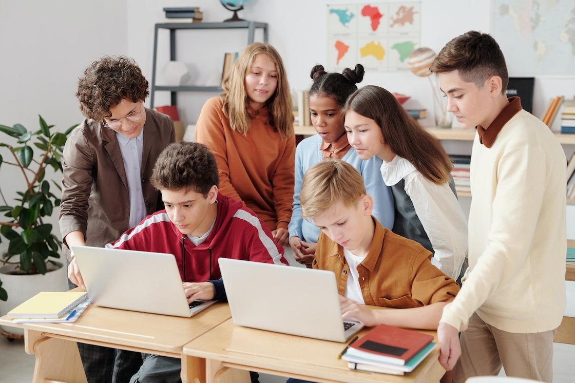 Подростки в школе смотрят в экран ноутбука