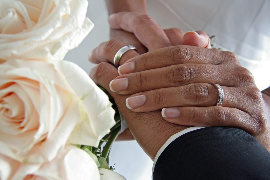 Руки жениха и невесты рядом с розами