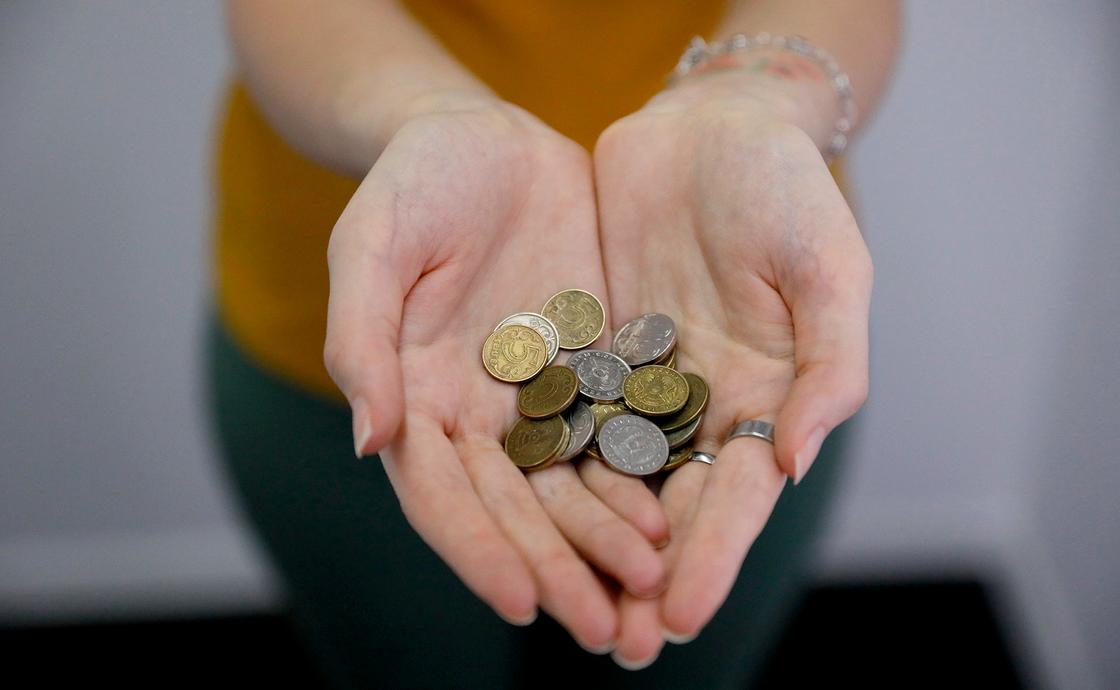 Девушка держит в руках монеты казахстанской валюты