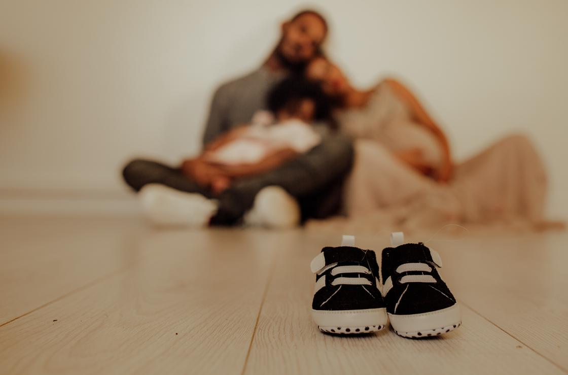 Мужчина и женщина сидят на полу и смотрят на пару детской обуви