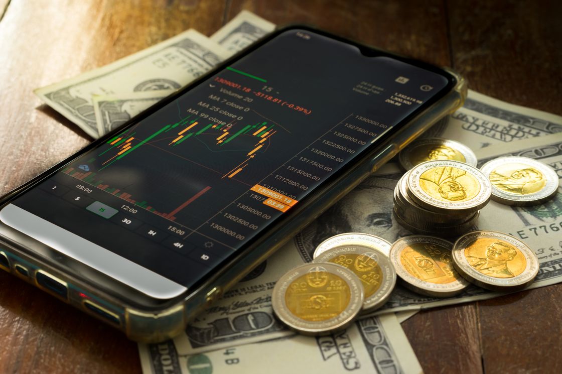 Смартфон с графиком лежит на долларах