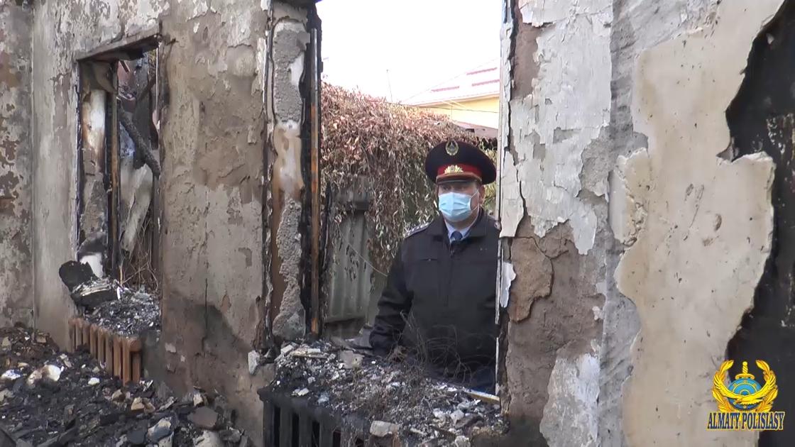 Полицейский стоит возле сгоревшего дома