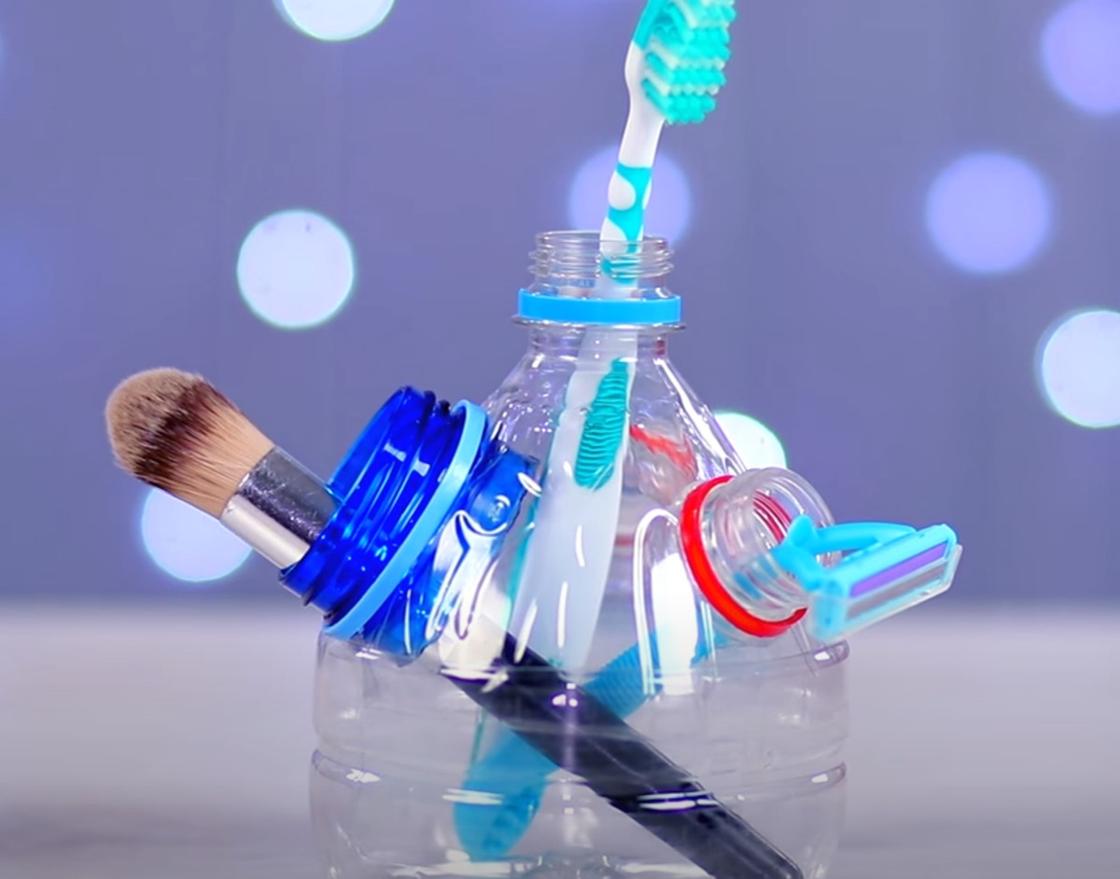 В подставке из верхушки пластиковой бутылки размещена зубная щетка, кисточка, станок