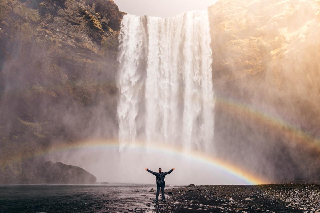 Человек на фоне радуги у водопада