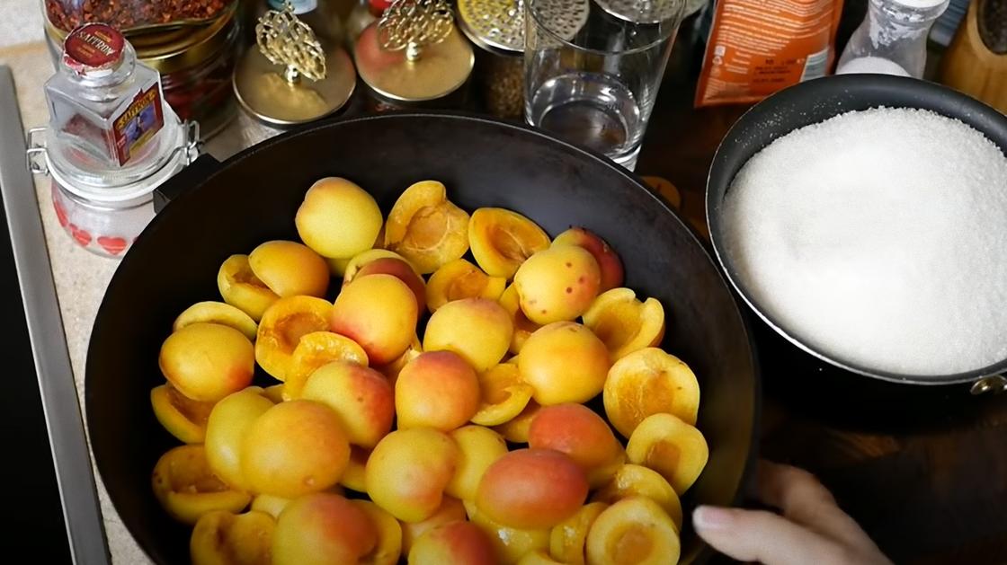 Половинки абрикосов в сковороде и сахар в миске