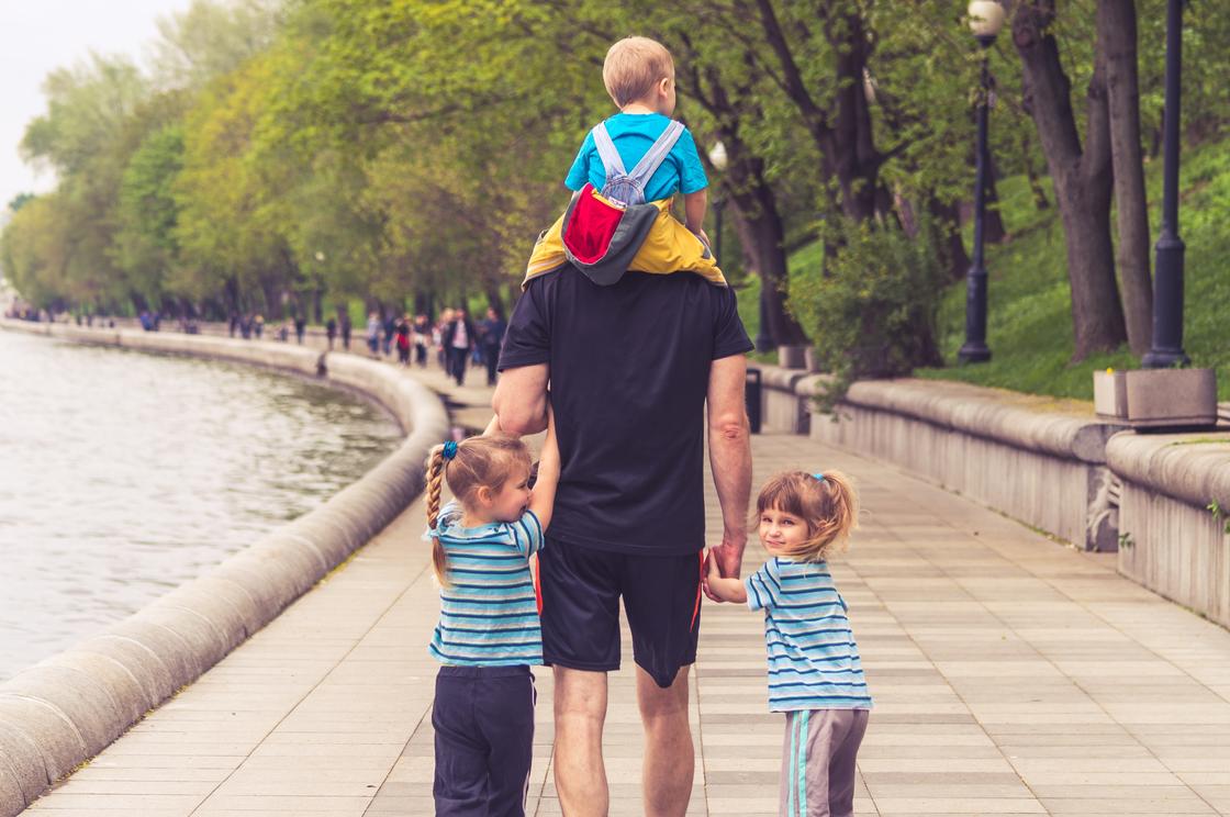 Отец и дети гуляют по набережной