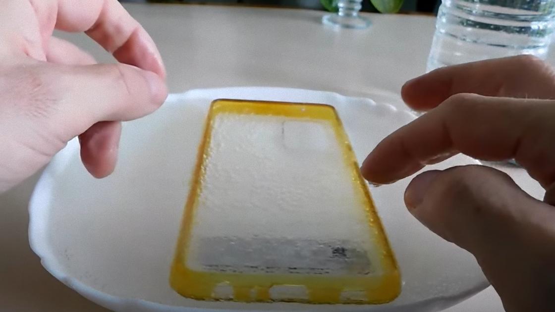 Пожелтевший прозрачный чехол окунают в миску с раствором