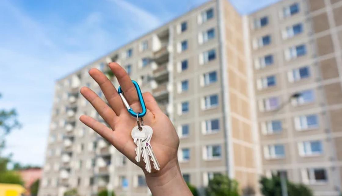 Ключи в руке на фоне дома