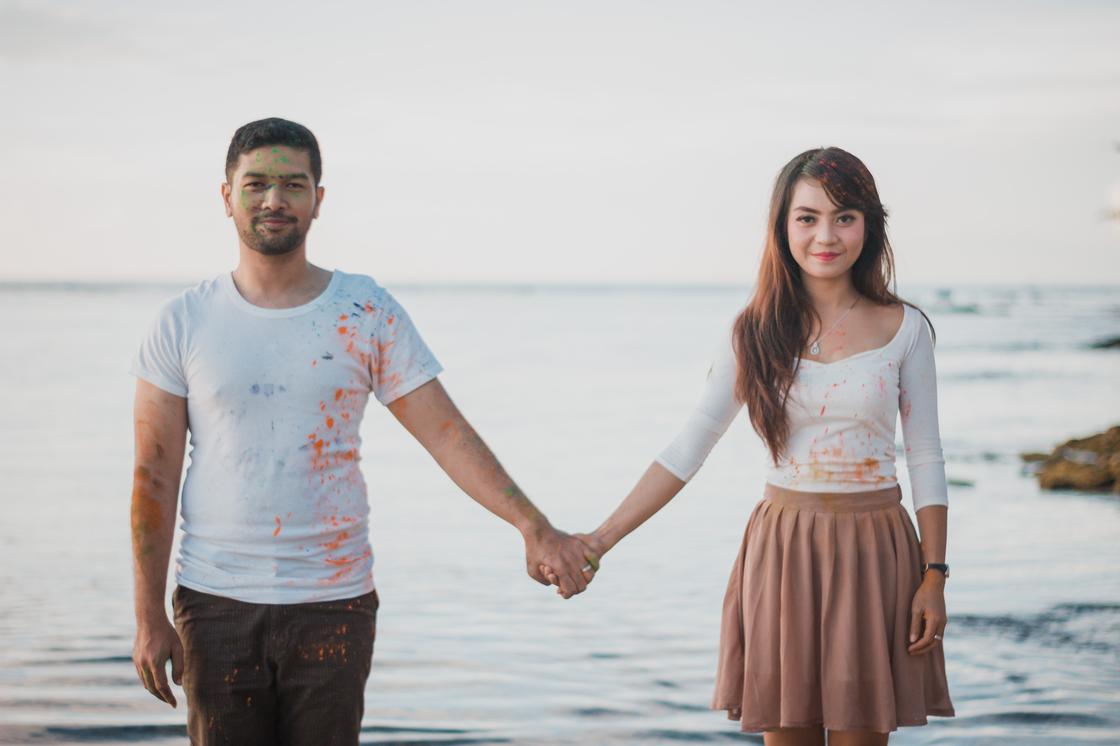 Мужчина и женщина держаться за руки на фоне водоема