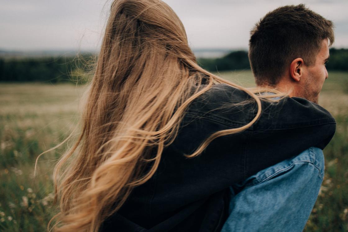 Парень и девушка с длинными волосами обнимаются в поле