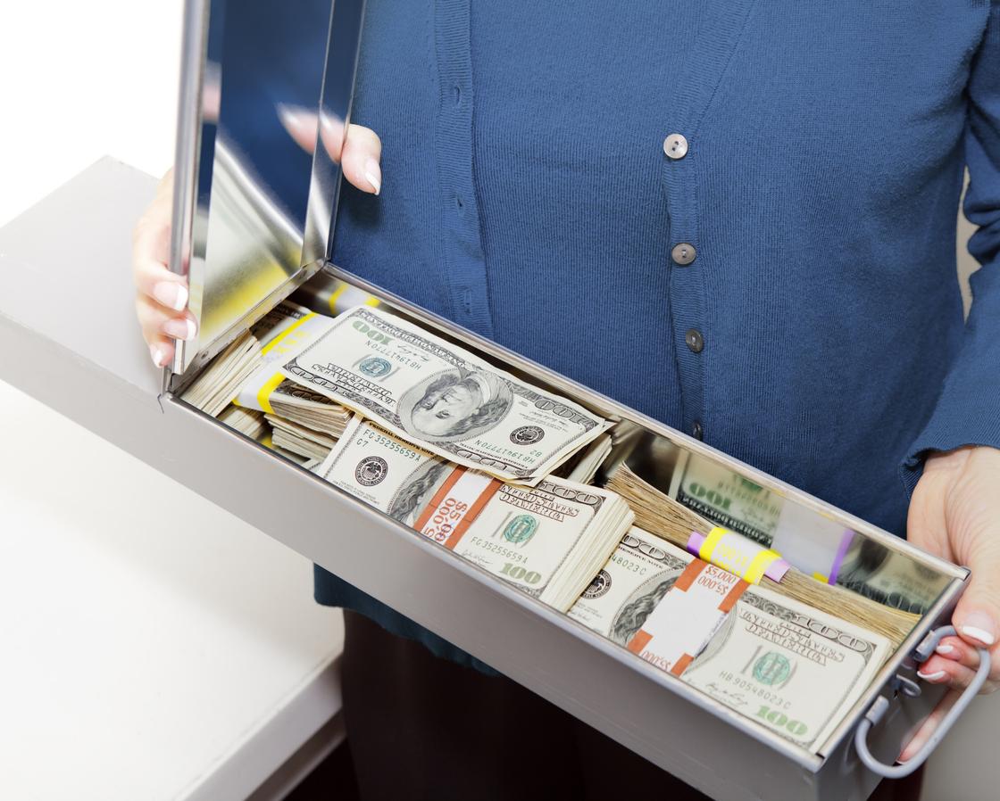 Женщина держит банковскую ячейку с долларами