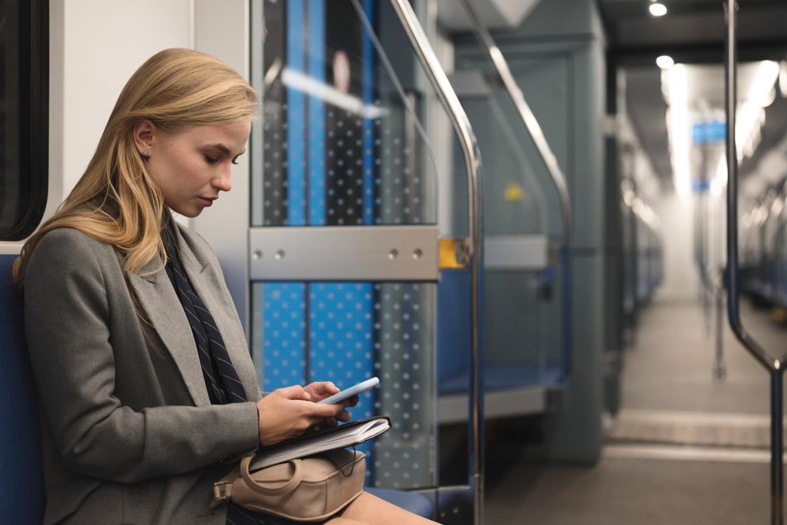 Девушка в вагоне метро смотрит в телефон