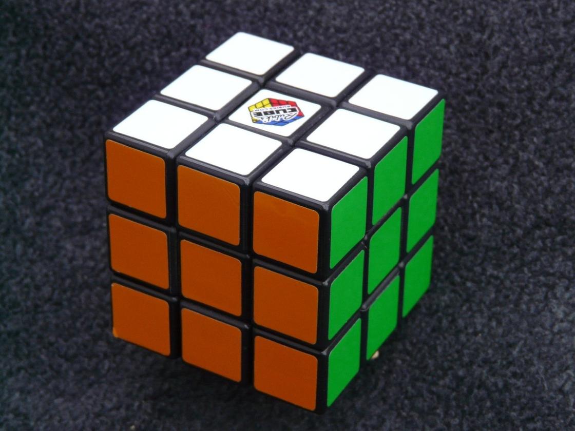 Кубик Рубика с собранными по одному цвету гранями. Кубик повернут оранжевой, зеленой и белой гранью